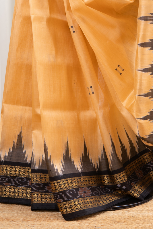 Gold saree with black and gold border on a woven surface